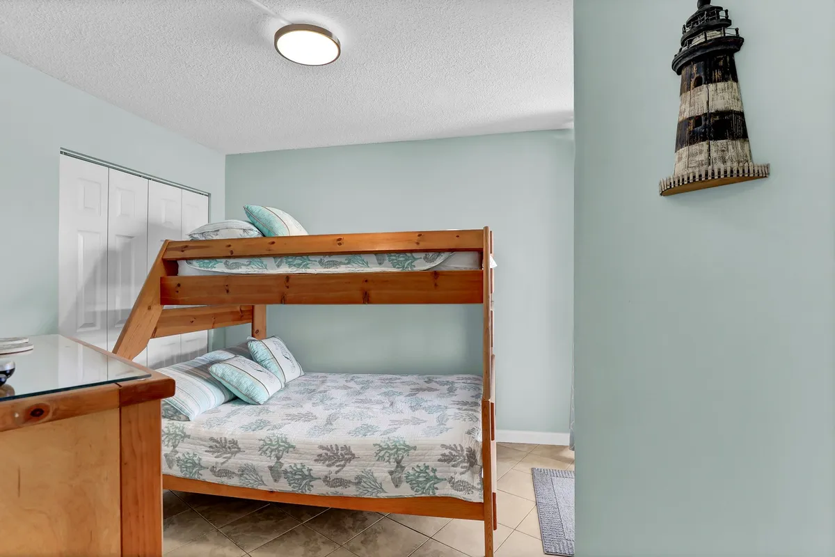 A playful bedroom featuring a bunk bed, lighthouse décor, and soft lighting. The lower bunk is a Full size while the upper is a Twin, creating a fun and welcoming space for kids and teens.